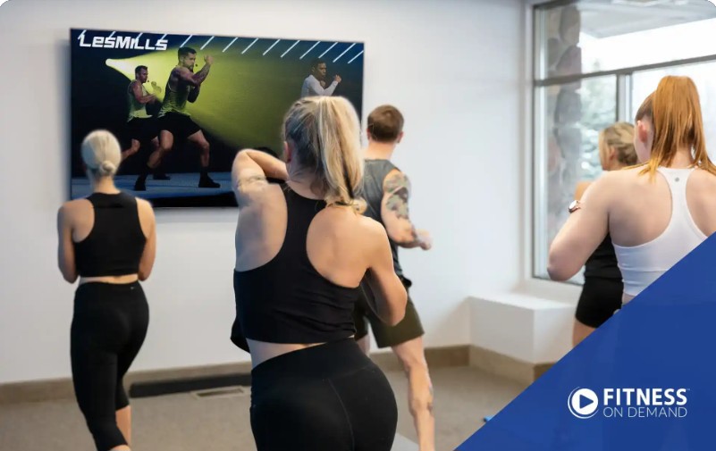 Image of small group exercising as they follow an online fitness class showing on a large screen tv
